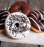 Delicious donuts with icing on napkin on wooden background