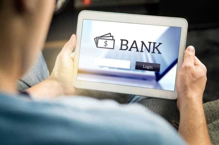 Man using mobile bank application with tablet and smart device at home. Login page to personal account. Online internet banking. Imaginary financial institution website or app.