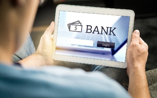 Man using mobile bank application with tablet and smart device at home. Login page to personal account. Online internet banking. Imaginary financial institution website or app.