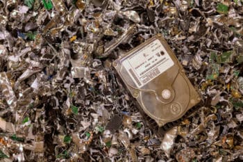 A hard drive resting on a pile of shredded hard drives