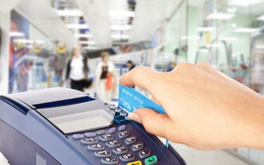 Human hand holding plastic card in payment machine in shop