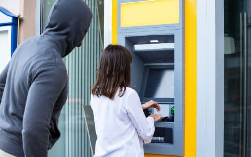 Thief Looking At Woman Entering The Pin In Atm