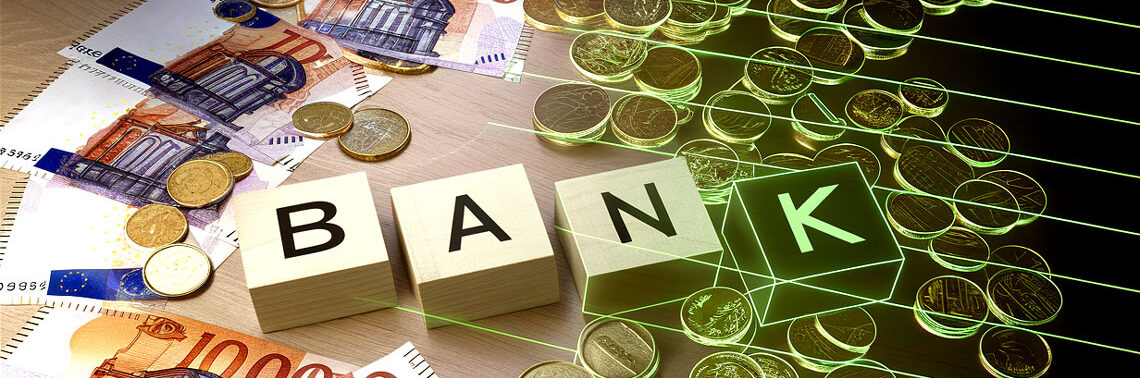 Bargeld und Münzen sind auf einer Oberfläche angeordnet, umgeben von Banknoten. Holzklötze bilden das Wort "BANK". Die Darstellung unterstreicht die Bedeutung von Bargeld als Zahlungsmittel im Handel.