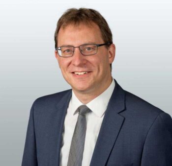 Das Bild zeigt Christian Brunner, einen Vertreter des Finanz Informatik Technologie Service (FI-TS). In einem Kontext, in dem FI-TS die Entwicklung einer eigenen Bare-Metal-Cloud betont, wird die Entscheidung, Kubernetes nicht den Hyperscalern zu überlassen, als strategischer Schritt hervorgehoben. Diese Initiative unterstützt die Cloud Native-Architektur und gewährleistet eine vollständige Mandantentrennung.