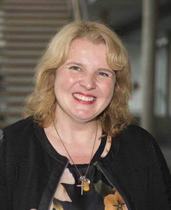 Dr. Christine Varga-Zschau von Rödl & Partner präsentiert sich lächelnd. Ihre Expertise wird im Kontext der Geldwäschebekämpfung und der neuen MiCA-Verordnung hervorgehoben, die regulatorische Rahmenbedingungen für Krypto-Transaktionen schafft.