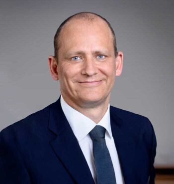 Geoffroy De Ridder, Technology and Operations Unit der Lombard Odier Group, präsentiert sich in formeller Kleidung. Die Modernisierung von Legacy-Systemen im Banken- und Finanzsektor erfordert innovative Ansätze, um regulatorische Anforderungen effizient zu erfüllen.