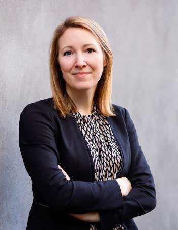 Georgina Neitzel, Leiterin Innovation Lab, ERGO Group. Das Bild zeigt sie mit verschränkten Armen, die in einem professionellen Umfeld steht. Sie trägt ein schwarzes Blazer und ein gemustertes Oberteil. Der Hintergrund ist neutral und unauffällig. Diese Darstellung könnte im Kontext des ERGO Innovation Lab stehen, das sich mit der systematischen Erprobung multimodaler GenKI beschäftigt.