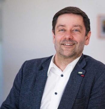 Rico Barth, Geschäftsführer von KIX Service Software, lächelt in die Kamera. Sein Auftreten vermittelt Zuversicht und Professionalität. In einem Kontext, in dem Donald Trump mit schlechten Umfragewerten konfrontiert ist, betont Barth die Notwendigkeit von Unabhängigkeit in Bezug auf die USA.