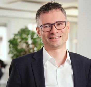 Stephan Schweizer, CEO bei Nevis Security, präsentiert sich in einem modernen Büro. Die Herausforderungen der NIS2-Richtlinie stellen insbesondere für Finanzinstitute eine erhebliche Belastung dar, während die Fristen für die nationale Umsetzung unklar bleiben.