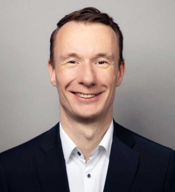 Sven Dost, Senior Manager bei Cofinpro, präsentiert sich in formeller Kleidung mit einem freundlichen Lächeln. Der Hintergrund ist neutral gehalten. In der aktuellen Diskussion zur Rolle von Künstlicher Intelligenz im Kreditprozess äußert er sich zu den Veränderungen in der Branche.