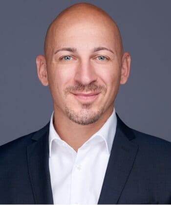 Thomas Stein, Wavestone, präsentiert sich in einem professionellen Umfeld. Sein Ausdruck vermittelt Selbstbewusstsein und Kompetenz. Im Kontext des neuen Geldwäschepakets der EU wird der Druck auf Finanzinstitute zur Einhaltung von Compliance-Vorgaben thematisiert.