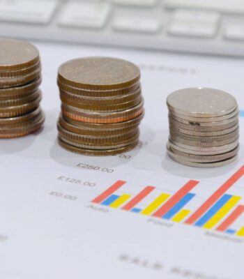 Stapelhaufen von Münzen unterschiedlicher Größe und Wert stehen auf einem Finanzbericht, der Diagramme und Zahlen enthält. Die visuelle Darstellung unterstreicht die Relevanz agiler Finanzentscheidungen im Treasury-Management.