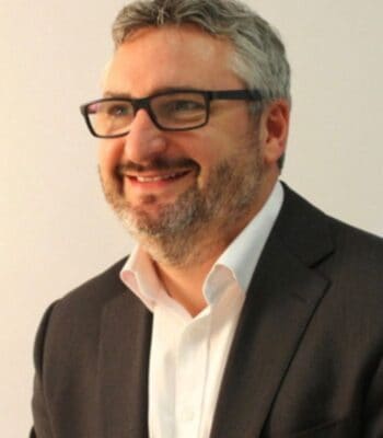 Andy Parsons, neuer Director EMEA Banking, Financial Services & Insurance bei CyberArk, lächelt in einem formellen Outfit. Der Hintergrund ist neutral gehalten, was den Fokus auf seine Person lenkt.