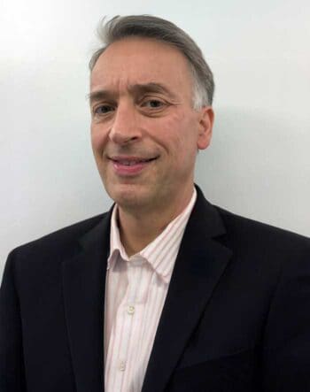 Armin Jesse (Experte für Rechenzentren) ist Head of Datacenter Engineering & Steering International bei T-Systems International, präsentiert sich in einem formellen Outfit. Der Hintergrund ist neutral gehalten, was den Fokus auf seine Person lenkt.