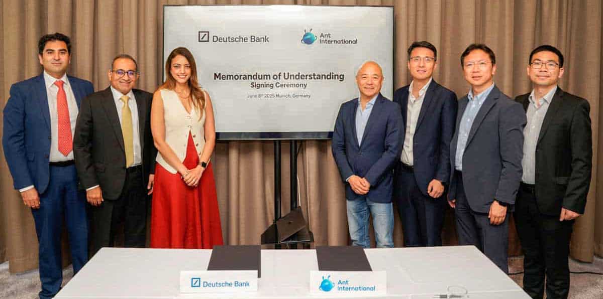 Bei der Unterzeichnung eines Memorandums of Understanding zwischen der Deutschen Bank und Ant International stehen mehrere Personen vor einem Bildschirm. Die Veranstaltung fand am 8. Juni 2025 in München, Deutschland, statt und zielt darauf ab, Zahlungslösungen in Europa und Asien anzubieten.