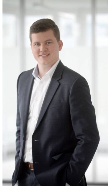 Fabian Hotarek, Pre-Sales bei CyberArk, steht in einem modernen Büro. Der Fokus liegt auf der Thematik der Schatten-KI, die durch unautorisierte KI-Tools von Mitarbeitern zusätzliche Sicherheitsrisiken in der IT-Sicherheit mit sich bringt.