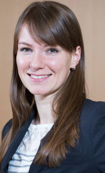 Maxi Harm, Senior Project Manager bei der KfW IPEX-Bank, präsentiert sich in professioneller Kleidung. Ihr Lächeln und der direkte Blick unterstreichen ihre Kompetenz im Bereich der Finanzierung von Rechenzentren, die für die digitale Infrastruktur entscheidend sind.