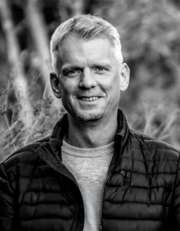 Mark Niemann, Geschäftsführer von Lamar GmbH, präsentiert sich in einem lässigen Outfit. Der Kontrast zwischen FinTech-Kultur und traditioneller Banken-IT wird deutlich, während er in einer entspannten Umgebung abgebildet ist.