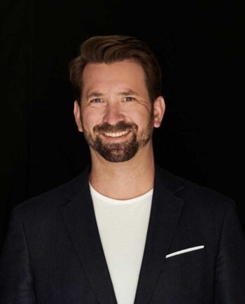 Roman Przibylla, Geschäftsführer der Maverix Security AG, präsentiert sich in einem formellen Outfit vor dunklem Hintergrund. Seine positive Ausstrahlung unterstreicht das Potenzial von Investitionen in innovative Technologien wie Quantum Computing.