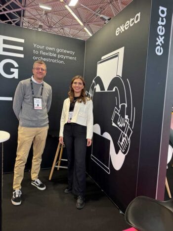 Auf der Money20/20 präsentiert Exxeta innovative Payment-Lösungen. Zwei Personen stehen vor einem Stand, der die Botschaft "Your own gateway to flexible payment orchestration" vermittelt. Der Fokus liegt auf digitalen Geschäftsprozessen und Plattformmodellen.