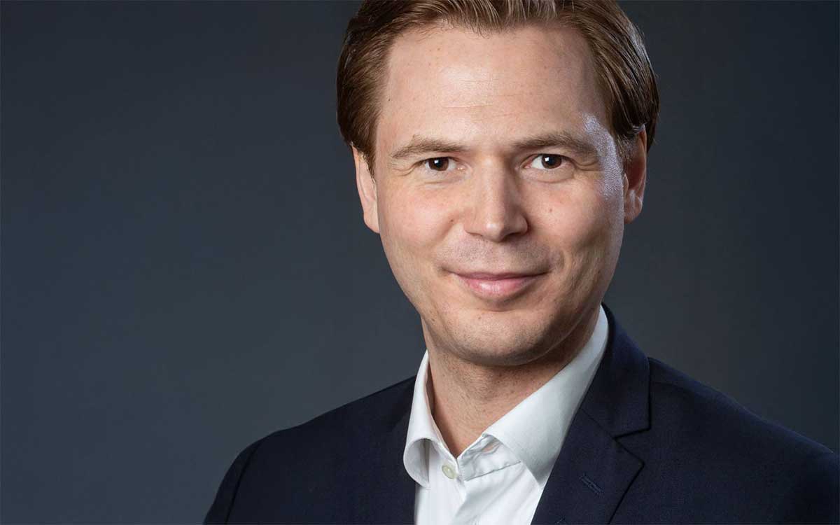 Markus Fehn, Leiter Strategie und Innovation bei Chartered Investment, präsentiert sich in einem professionellen Porträt. Der Fokus liegt auf seiner Person, die in einem formellen Outfit vor einem neutralen Hintergrund abgebildet ist. Tokenisierung ist ein zentrales Thema seiner Arbeit.