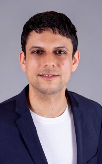Sanjay Bollmann, Director und Customer Unit Leader für Banking & Insurance bei Kyndryl, präsentiert sich in einem professionellen Umfeld. Der Fokus liegt auf der Transformation des Zahlungsverkehrs durch neue Technologien und digitale Lösungen.