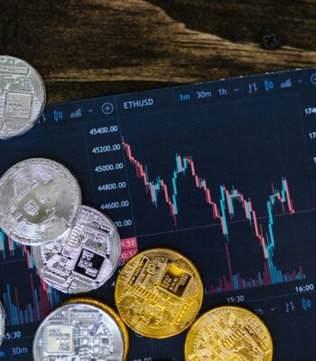 Die Abbildung zeigt eine Auswahl von Kryptowährungen, darunter Bitcoin und Ethereum, auf einem digitalen Chart, der Preisschwankungen darstellt. Diese Darstellung ist relevant im Kontext der Blockchain-basierten Anleihe der NRW-Bank.