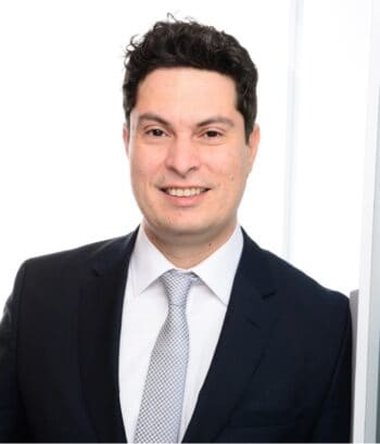 Dr. Ivan Monahov, Executive Partner und Bereichsleiter bei msg for banking, präsentiert sich in formeller Kleidung. Sein Lächeln und die professionelle Haltung unterstreichen die Bedeutung von Cloud-Lösungen für die digitale Resilienz in der Finanzbranche.