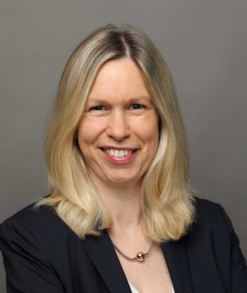 Dr. Rauner, zukünftige Chief Information Officer und Chief Operating Officer der Helaba, präsentiert sich mit einem freundlichen Lächeln. Sie trägt eine dunkle Blazerjacke und hat lange, blonde Haare. Der Hintergrund ist neutral gehalten.