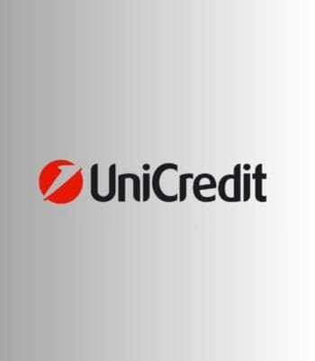 Das Bild zeigt das Logo von UniCredit, bestehend aus einem roten Kreis mit einem weißen Blitzsymbol und dem Schriftzug „UniCredit“ in schwarzer Schrift. Der Hintergrund ist in einem sanften Grauton gehalten.