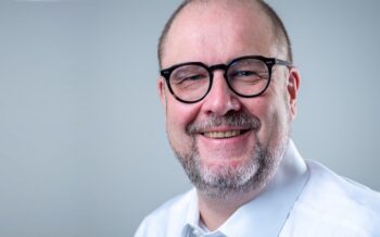 Udo Browarczik, Business Analyst, präsentiert sich lächelnd. Seine Expertise im Zahlungsverkehr und in SWIFT-Infrastrukturen ist relevant für die Diskussion über ISO 20022. Der Fokus liegt auf strategischen Ansätzen zur Implementierung.