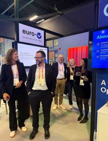 Auf der SIBOS 2025 präsentiert EuroV, ein Unternehmen mit Wurzeln in der van den Berg GmbH, innovative Ansätze zu Agentic Payments. Die Abbildung zeigt mehrere Teammitglieder am Messestand, die aktiv im Austausch sind.
