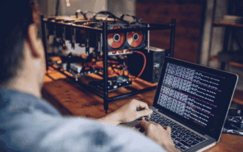 Crypto Risk Metrics Grafik zeigt einen Mann am Laptop der eine Maschine zu programmieren scheint.