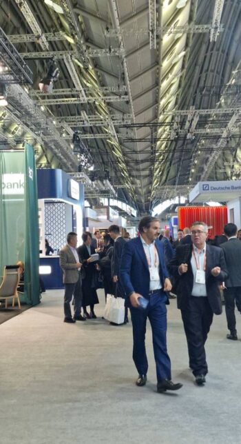 Im Rahmen der Sibos 2025 sind Fachbesucher in einer Messehalle zu sehen, die sich über aktuelle Entwicklungen in der Finanzbranche austauschen. Stände von Banken und Unternehmen sind im Hintergrund sichtbar, was die Innovationskraft der Branche unterstreicht.