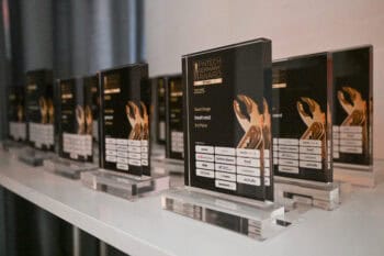 Die Auszeichnungen des Fintech Germany Award 2025 sind auf einem Tisch angeordnet. Jede Trophäe zeigt den Namen des jeweiligen Preisträgers sowie die Kategorie. Die Veranstaltung würdigt die vielversprechendsten FinTech-Startups und Scaleups in Deutschland.
