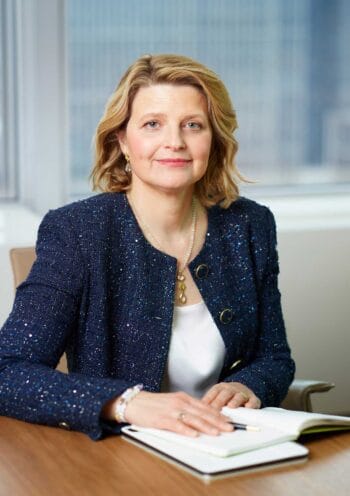 Fritzi Köhler-Geib, Vorständin der Bundesbank, posiert am Tisch mit einem Notizbuch. Ihr Blick ist direkt und konzentriert. Die Darstellung unterstreicht die Bedeutung von Resilienz in der aktuellen wirtschaftlichen Diskussion.