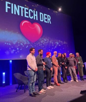 Auf der DigiFin25 in Berlin stehen mehrere Personen auf der Bühne, umgeben von einer festlichen Atmosphäre. Im Hintergrund ist der Schriftzug „Fintech der Herzen“ zu sehen. Die Veranstaltung würdigt bedeutende Akteure der Fintech-Branche.