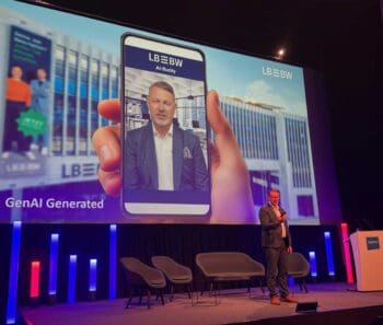 Auf der Bühne präsentiert Stephan Paxmann, Chief Innovation Officer der LBBW, einen digitalen Assistenten für die Vermögensverwaltung. Im Hintergrund ist eine Darstellung des LBBW-Gebäudes und der App „AI-Buddy“ zu sehen.
