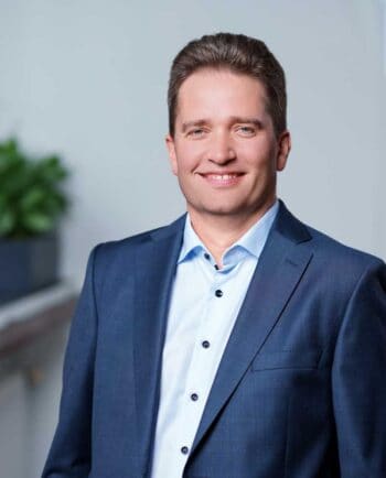 Martin Jäger, Chief Information Security Officer bei G+D Netcetera, präsentiert sich in formeller Kleidung. Der Hintergrund ist neutral gehalten, was die Professionalität unterstreicht. Compliance-Themen stehen im Fokus seiner Tätigkeit.