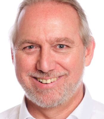 Michael Baldauf, Financial Services Senior Director bei Pegasystems, wird abgebildet. Er thematisiert die Rolle von KI-Agenten in Banken, die für die einheitliche Bearbeitung von Anfragen und die Vermeidung von Reputationsschäden verantwortlich sind.