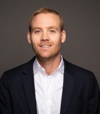 Tim van Lier, neuer Mitarbeiter bei Baobab Insurance, präsentiert sich in einem formellen Outfit. Der Hintergrund ist neutral gehalten, was den Fokus auf seine Person lenkt. Sein Lächeln vermittelt Professionalität und Offenheit.