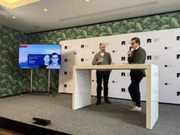 Im Rahmen der Veranstaltung Frankfurt Digital Finance stehen sich Gäste an einem Stehtisch gegenüber. Auf einem Bildschirm im Hintergrund sind ihre Namen und Funktionen angezeigt. Die Atmosphäre ist professionell und informativ.