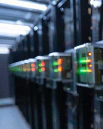 Die Abbildung zeigt eine Reihe von Servern in einem Rechenzentrum. Die Geräte sind mit grünen und roten Lichtern ausgestattet, die Betriebszustände anzeigen. VR Factoring unterstützt Unternehmen bei der IT-Migration zu modernen Kernbanksystemen.