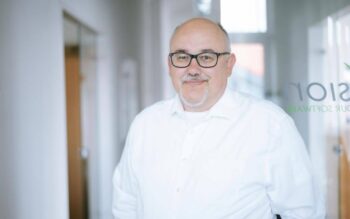 Jürgen Bernert, Geschäftsführer von Avision, steht in einem modernen Büro. Er trägt ein weißes Hemd und hat eine Brille auf. Der Hintergrund zeigt eine helle, offene Büroatmosphäre. Die Expertise in der Modernisierung von Legacy IT wird durch seine Präsenz unterstrichen