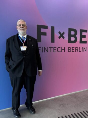 Hans-Rainer van den Berg, Sovereignity vdB, steht vor einem farblich gestalteten Hintergrund mit der Aufschrift „FI x BE FINTECH BERLIN“. Die Veranstaltung betont die Bedeutung von KI und internationalen Netzwerken im Bankensektor.