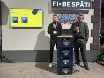 Zwei Referenten stehen an einem Podium während der FIBE 2026. Im Hintergrund wird das Thema "Digitale Geschäftsmodelle: Zwischen Regulierung und Innovation" präsentiert. Die Veranstaltung fördert den Austausch über aktuelle Trends in der Bankenbranche.