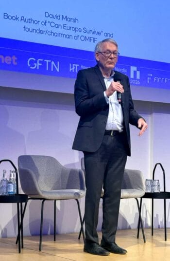 David Marsh, Buchautor von „Can Europe Survive?“ und Vorsitzender von OMFIF, spricht auf der Veranstaltung Fintech Copenhagen x GFTN in Berlin. Im Hintergrund sind Stühle und Wasserflaschen sichtbar, während er das Publikum adressiert.