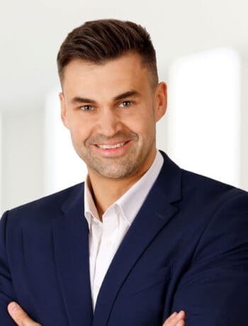 Dennis Schmidt, Head of Real Estate Management bei der Finanz Informatik, präsentiert sich in einem professionellen Umfeld. Seine Rolle umfasst die Entwicklung eines IT-Ökosystems zur Optimierung von Geschäftsprozessen im Immobiliensektor.