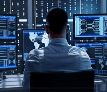 Ein IT-Sicherheitsexperte überwacht mehrere Bildschirme in einem Kontrollraum. Die Displays zeigen Datenanalysen und Netzwerkinformationen, die für die Sicherheitsoperationen von Unternehmen, einschließlich Lösungen von SentinelOne, relevant sind.