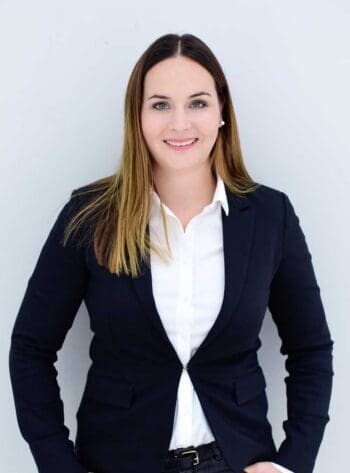 Lisa Weinert, Mitarbeiterin der msg for banking ag, präsentiert sich in formeller Kleidung. Ihr Lächeln und die aufrechte Haltung vermitteln Professionalität. Im Kontext der DORA-Compliance spielt sie eine Rolle in der Förderung operativer Resilienz.